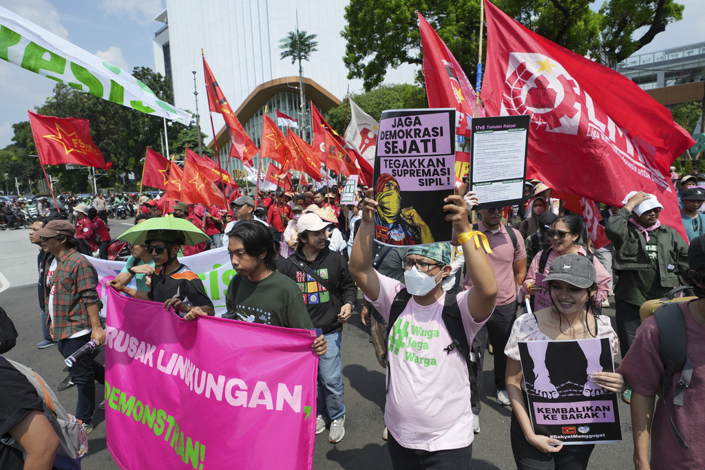 Protesters march as some hold a banner with writing reading "Guard democracy, uphold civil supremacy" during a protest against food price hikes and soaring taxes in Jakarta, Indonesia, Thursday, Sept. 4, 2025. (AP Photo/Achmad Ibrahim)