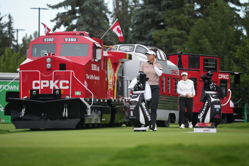 Miyu Yamashita, back right, of Japan, walks past a mini CPKC train as she arrives at the first tee behind Hannah Green, of Australia, during the first round at the LPGA Canadian Women's Open golf tournament in Edmonton, Alberta, Thursday, Aug. 20, 2026. (Darryl Dyck/The Canadian Press via AP)