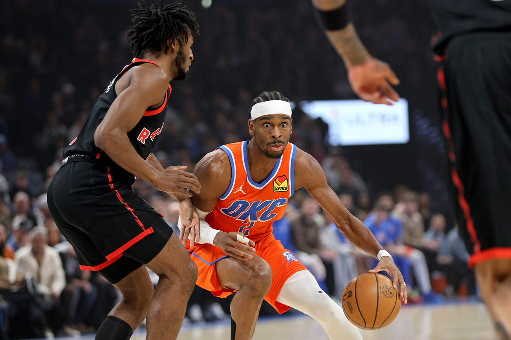 Oklahoma City Thunder guard Shai Gilgeous-Alexander, center, handles the ball against Toronto Raptors guard Immanuel Quickley, left, during the first half of an NBA basketball game Sunday, Jan. 25, 2026, in Oklahoma City. (AP Photo/Nate Billings)