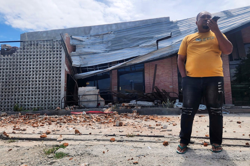 A man talks on his mobile phone near a building damaged in an earthquake in Palu, Central Sulawesi, Tuesday, June 16, 2026. (AP Photo/Josua Marunduh)