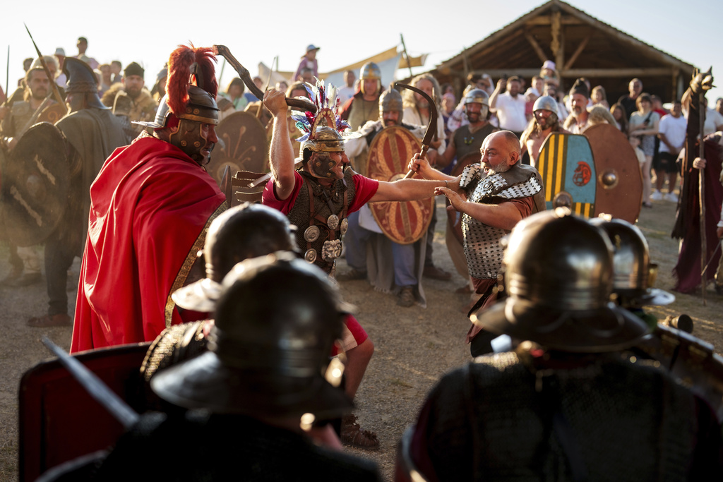 Members of historical reenactment groups wearing Dacian warrior and Roman soldiers outfits, clash in Poiana, Romania, Sunday, July 13, 2025, during the Getodava historical reenactment festival. (AP Photo/Vadim Ghirda)