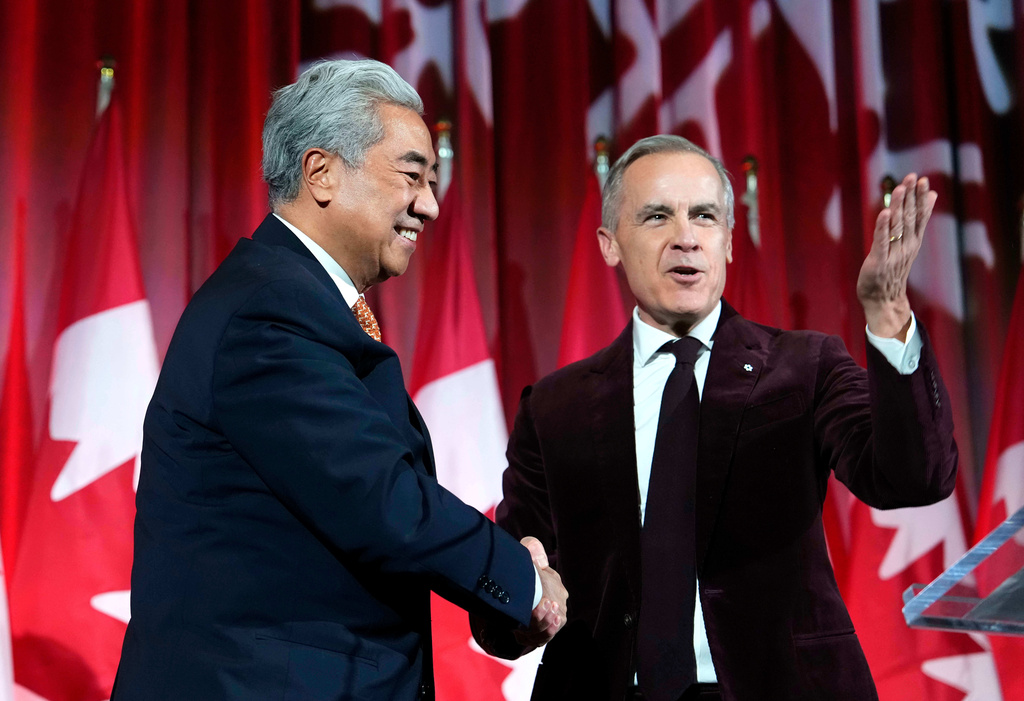 Canadian Prime Minister Mark Carney, right, shakes hands with Michael Ma, Member of Parliament for Markham-Unionville, who crossed the floor from the Conservatives to the Liberals hours earlier, as he brings him on stage at the Liberal caucus holiday party in Ottawa, Ontario, Thursday, Dec. 11, 2025. (Justin Tang/The Canadian Press via AP)