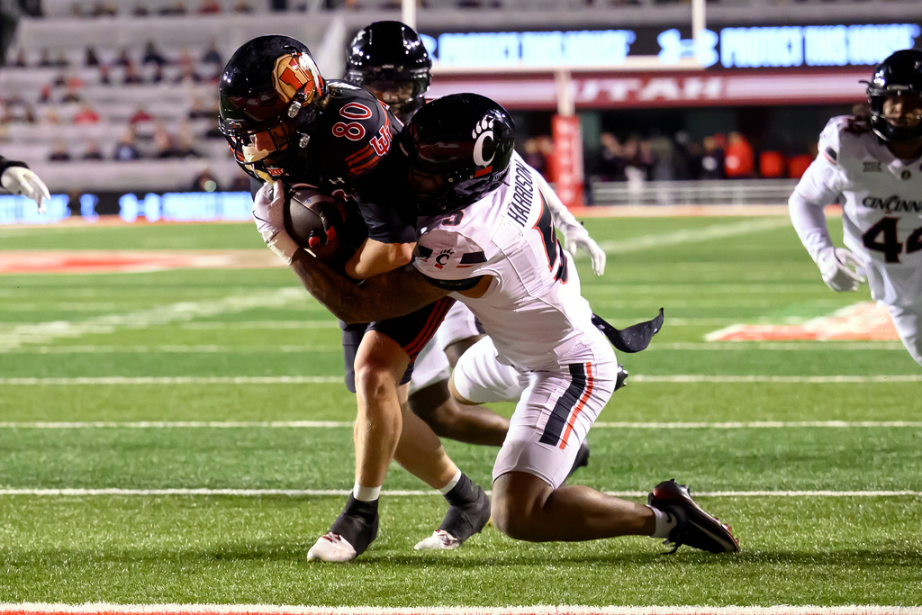 Utah wide receiver Creed Whittemore (80) runs the football after a catch into the end zone as Cincinnati safety Christian Harrison (5) attempts to make a tackle during the second half an NCAA college football game, Saturday, Nov. 1, 2025, in Salt Lake City, Utah. (AP Photo/Tyler Tate)