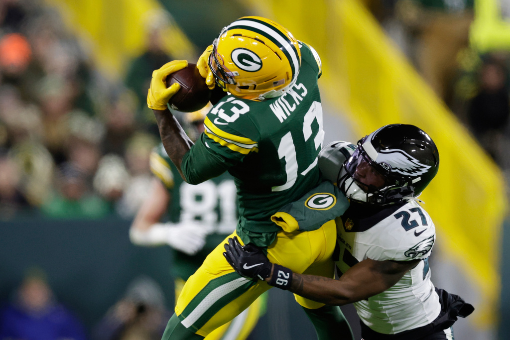 Green Bay Packers wide receiver Dontayvion Wicks (13) catches a first down pass against Philadelphia Eagles cornerback Quinyon Mitchell (27) during the second half of an NFL football game Monday, Nov. 10, 2025, in Green Bay, Wis. (AP Photo/Matt Ludtke)