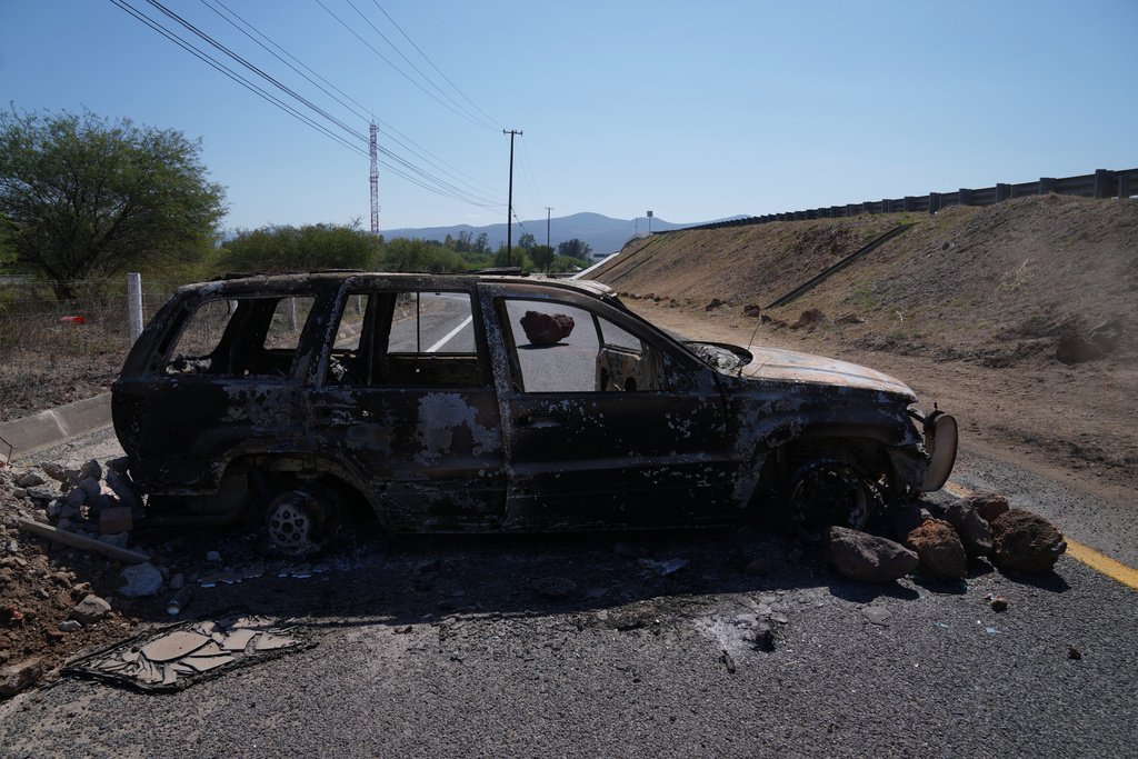 A burned vehicle blocks a road leading to Tapalpa, Mexico, Monday, Feb. 23, 2026, a day after the Mexican army killed Jalisco New Generation Cartel leader Nemesio Oseguera Cervantes, known as "El Mencho."(AP Photo/Marco Ugarte)