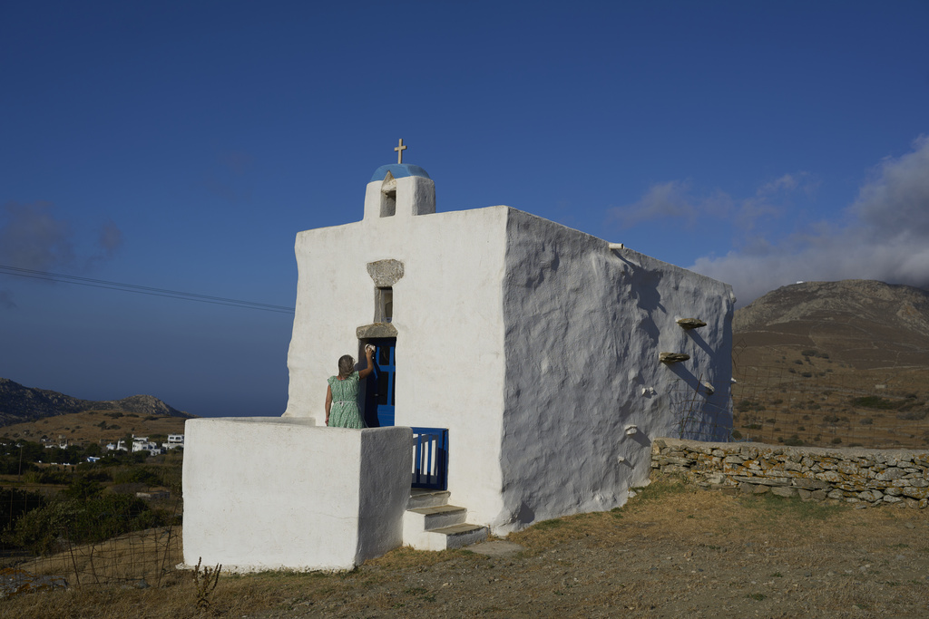 Bernadette Foskolos cleans her Agios Athanasios family-owned chapel at the village of Steni, on the island of Tinos, Greece, Saturday, Sept. 6, 2025. (AP Photo/Petros Giannakouris)