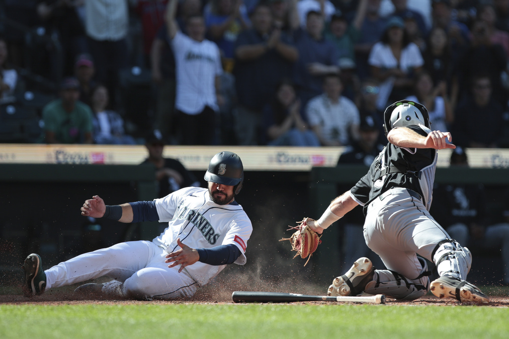 Seattle Mariners' Eugenio Suárez, left, beats a tag by Chicago White Sox catcher Kyle Teel, right, to score the winning run off a hit by Dominic Canzone during the 11th inning of a baseball game, Thursday, Aug. 7, 2025, in Seattle. (AP Photo/Jason Redmond)