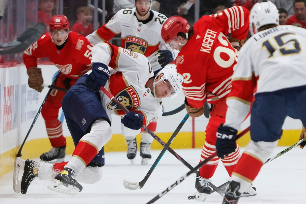 Florida Panthers defenseman Niko Mikkola (77) tries to clear the puck against Detroit Red Wings center Marco Kasper (92) during the second period of an NHL hockey game Friday, March 6, 2026, in Detroit. (AP Photo/Duane Burleson)