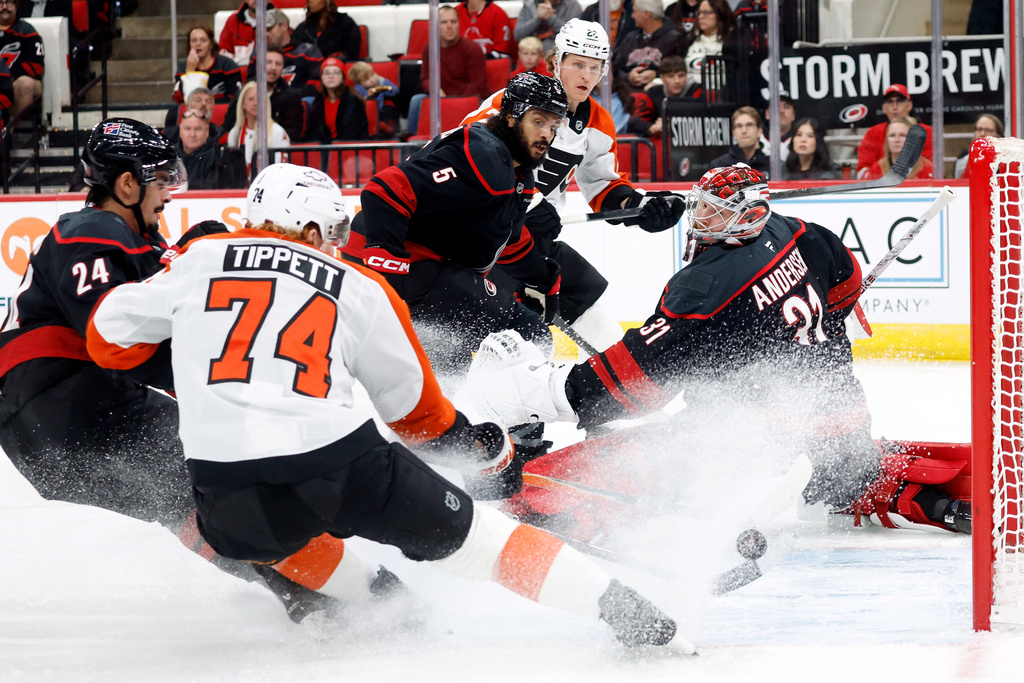 Carolina Hurricanes' Seth Jarvis (24) tips the puck over Philadelphia Flyers' Owen Tippett's (74) stick while goaltender Frederik Andersen (31), Carolina Hurricanes' Jalen Chatfield (5) and Philadelphia Flyers' Christian Dvorak (22) look on during the first period of an NHL hockey game in Raleigh, N.C., Saturday, Oct. 11, 2025. (AP Photo/Karl DeBlaker)