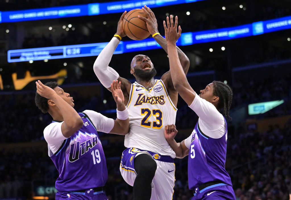 Los Angeles Lakers forward LeBron James (23) is defended by Utah Jazz guard Ace Bailey, left, and Jazz forward Cody Williams as he drives to the basket during the first half of an NBA basketball game Sunday, April 12, 2026, in Los Angeles. (AP Photo/Jayne Kamin-Oncea)