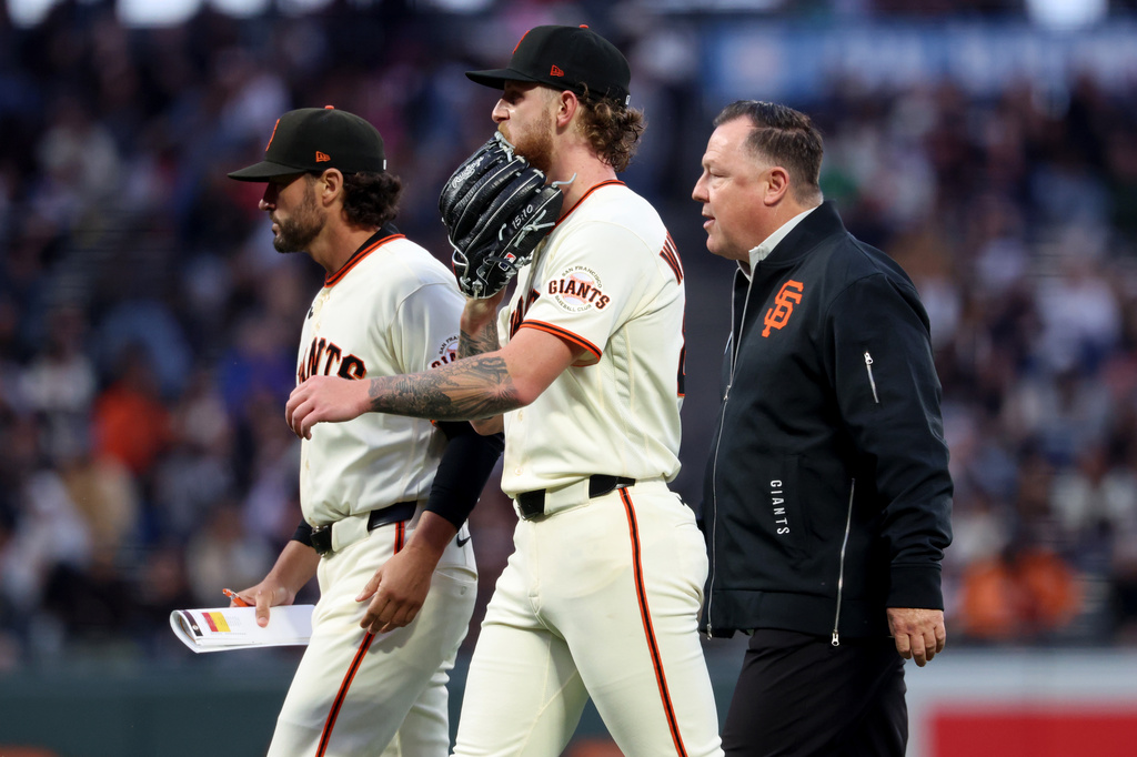 San Francisco Giants pitcher Carson Whisenhunt, center, walks off the mound with manager Tony Vitello, left, and Dave Groeschner, vice president of medical & performance, during the third inning of a baseball game against the Cincinnati Reds in San Francisco, Monday, Aug. 24, 2026. (AP Photo/Jed Jacobsohn)