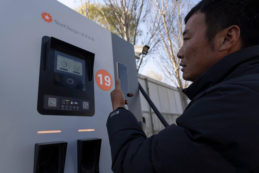 A driver operates a charging station to charge his electric truck on the outskirts of Beijing, on Nov. 14, 2025. (AP Photo/Ng Han Guan)