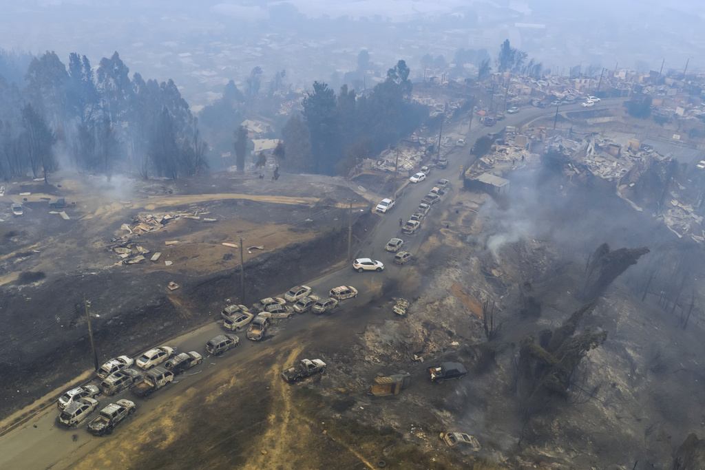 Damaged vehicles line a road after wildfires swept through residential areas in Lirquen, Chile, Sunday, Jan. 18, 2026. (AP Photo/Javier Torres)