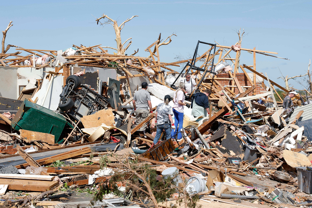 A family looks through debris of their home Friday, April 24, 2026, in the Grayridge neighborhood that was damaged by a tornado Thursday in Enid, Okla. (AP Photo/Alonzo Adams)