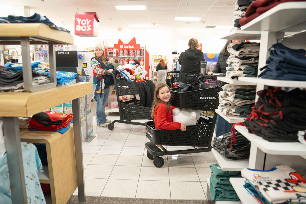Eva Klein sits in the bottom of her grandmothers shopping cart as shoppers browse through Kohl's department store for Black Friday, Friday, Nov. 28, 2025, in Woodstock, Ga. (AP Photo/Megan Varner)