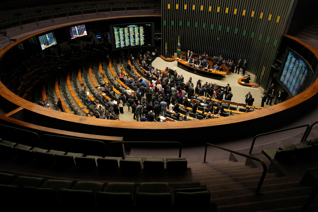 Congresspeople attend a session to consider a bill to alter the sentencing guidelines for crimes including leading a coup d'état, for which former President Jair Bolsonaro was sentenced, in Brasilia, Brazil, Tuesday, Dec. 9, 2025. (AP Photo/Eraldo Peres)