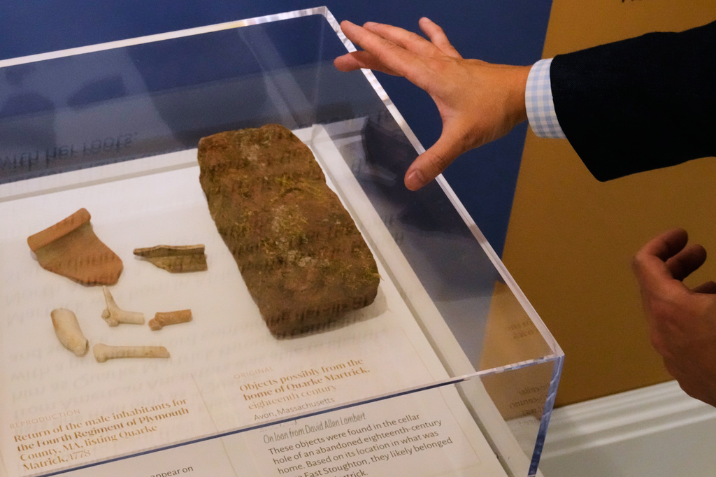 Ryan J. Woods, President & Chief Executive Officer of the American Ancestors museum, gestures to artifacts, believed to be from the residence of a black soldier who fought in the Revolutionary War, during a tour of the "Patriots of Color" exhibition at the museum, Wednesday, April 15, 2026, in Boston. (AP Photo/Charles Krupa)