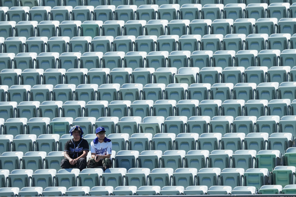 Los Angeles Dodgers fans look on among empty seats as they shield themselves from the sun and heat before Game 1 of a National League Division Series baseball game against the Atlanta Braves Saturday, Oct. 3, 2026, in Los Angeles. (AP Photo/Jae C. Hong)