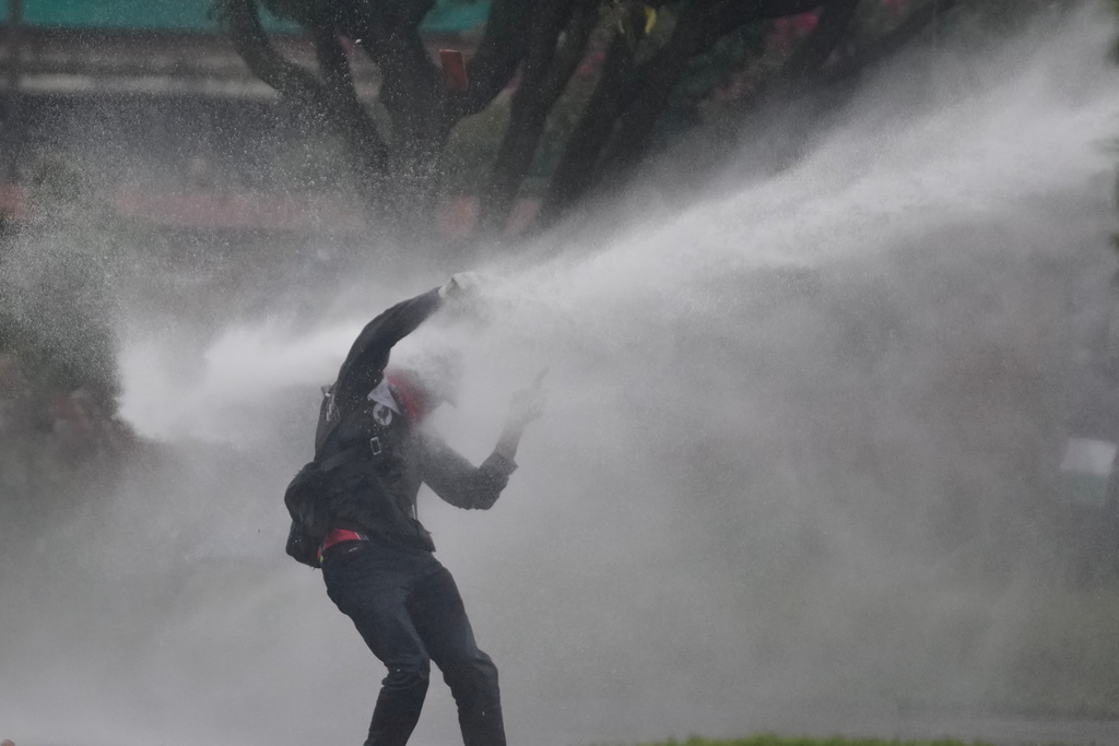 FILE - A demonstrator is hit by a jet stream of water from a police water cannon during a protest demanding action from President Gustavo Petro's government on social, environmental and security issues in Bogota, Colombia, Oct. 17, 2025. (AP Photo/Fernando Vergara, File)