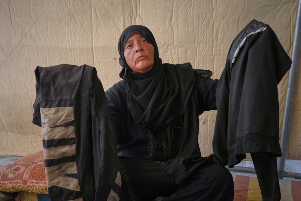 Fadwa al-Ghalban holds clothes belonging to her son, Mosaab, at her tent in Muwasi, along Gaza's southern coast, Oct. 3, 2025. Fadwa has had no word from Mosaab since July, when his cousins last saw him near their house as an Israeli strike destroyed it in the southern town of Maan. (AP Photo/Jehad Alshrafi)