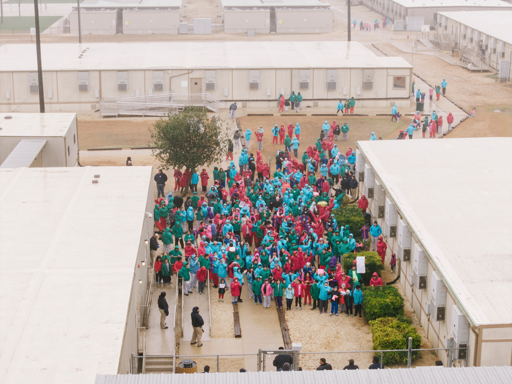 Detainees held at the South Texas Family Residential Center wave signs during a demonstration in Dilley, Texas, Saturday, Jan. 24, 2026. (AP Photo/Brenda Bazán)