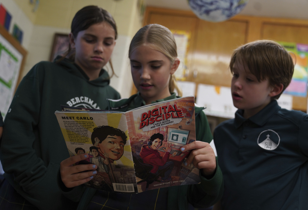 Fifth grade students, Paulie Alfirevich, left, Paige Lange, center, and Alex Miller, read a comic book about the life of Blessed Carlo Acutis, who will be canonized a saint by Pope Leo XIV, entitled "Digital Disciple" during a class activity at St. John Berchmans' school on Wednesday, Sept. 3, 2025, in Chicago. (AP Photo/Jessie Wardarski)