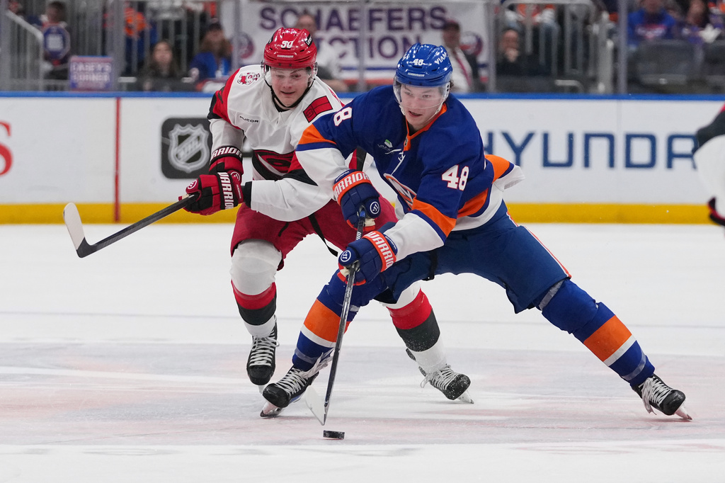 New York Islanders' Matthew Schaefer (48) drives past Carolina Hurricanes' Eric Robinson (50) during the second period of an NHL hockey game Tuesday, April 14, 2026, in Elmont, N.Y. (AP Photo/Frank Franklin II)