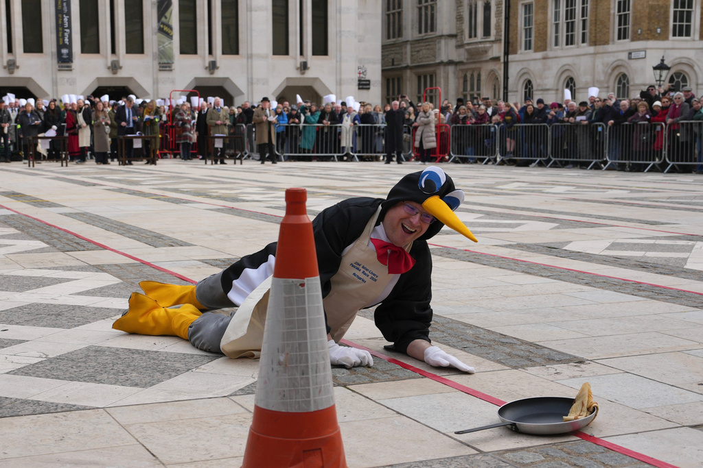 A competitor falls down during a traditional pancake race by livery companies at the Guildhall in London, Tuesday, Feb. 17, 2026. (AP Photo/Kin Cheung)