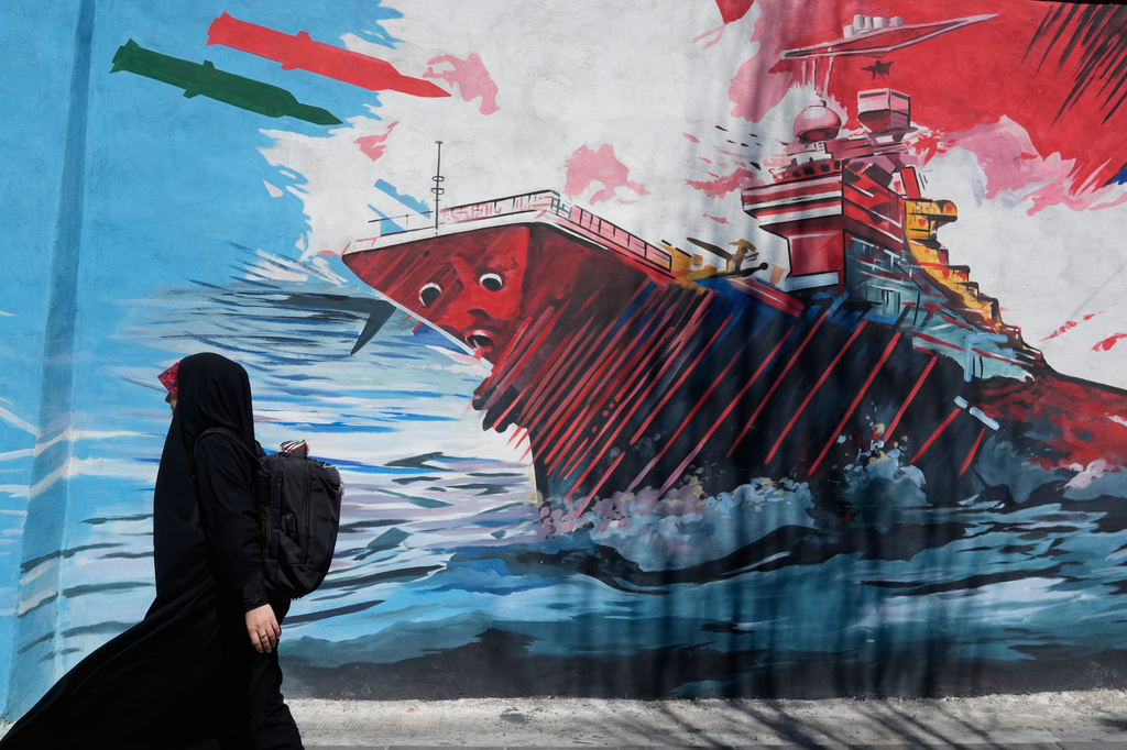 A woman walks past a mural depicting a U.S. aircraft carrier under missile attack in downtown Tehran, Iran, Monday, June 8, 2026. (AP Photo/Vahid Salemi)