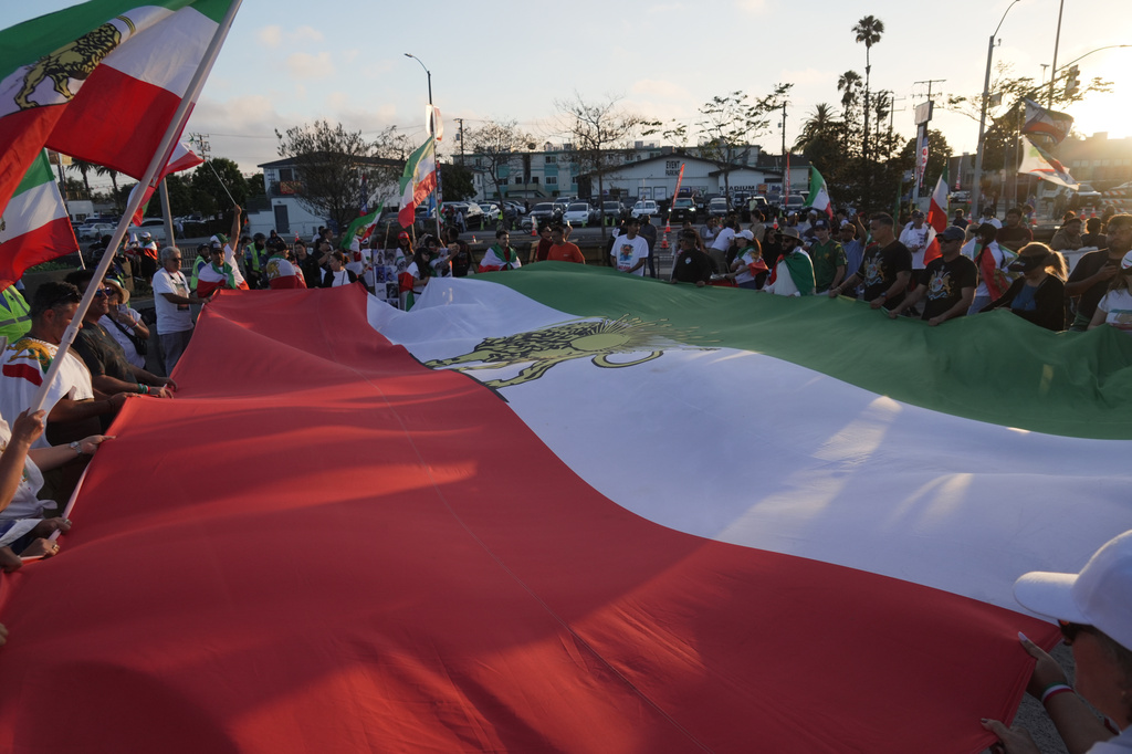 People unfurl a large Pre-revolutionary Iranian flag during a protest outside Los Angeles Stadium before the World Cup Group G soccer match between Iran and New Zealand in Inglewood, Calif., near Los Angeles, Monday, June 15, 2026. (AP Photo/Ty ONeil)