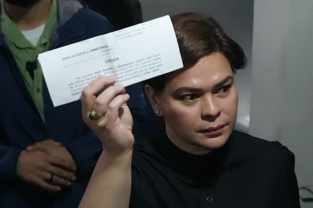 Philippine Vice President Sara Duterte shows a document to reporters at the Quezon city justice hall Saturday, Sept. 5, 2026, after an arrest warrant was issued on charges that she publicly threatened to have the president and two other people assassinated. (AP Photo/Aaron Favila)