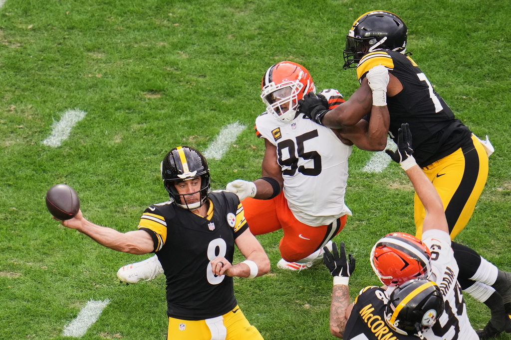 Pittsburgh Steelers quarterback Aaron Rodgers (8) passes under pressure from Cleveland Browns defensive end Myles Garrett (95) in the second half of an NFL football game in Pittsburgh, Sunday, Oct. 12, 2025. (AP Photo/Gene J. Puskar)