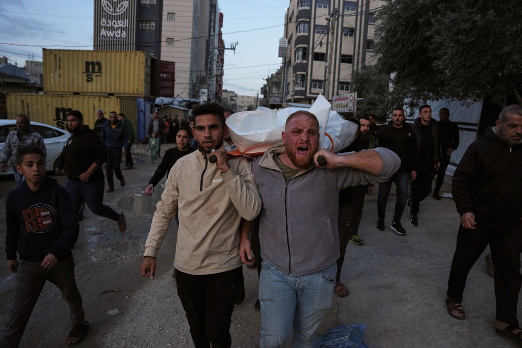 Mourners carry the body of Ahmed Hamdan Tabasha, a Palestinian policeman killed in an Israeli military strike, during his funeral at Al-Awda Hospital in Nuseirat, southern Gaza Strip, Sunday, March 22, 2026. (AP Photo/Abdel Kareem Hana)