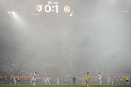 Smoke floats over the pitch during the Bundesliga soccer match between FC Augsburg and Borussia Dortmund in Augsburg, Germany, Friday, Oct. 31, 2025. (AP Photo/Matthias Schrader) Smoke floats over the pitch during the Bundesliga soccer match between FC Augsburg and Borussia Dortmund in Augsburg, Germany, Friday, Oct. 31, 2025. (AP Photo/Matthias Schrader)