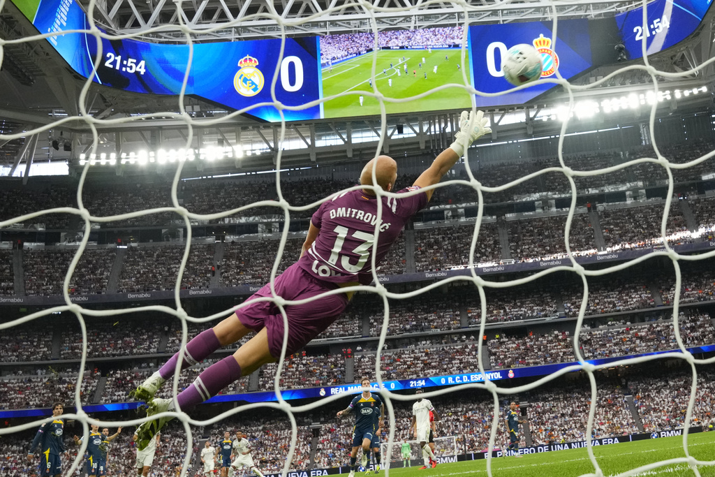 Espanyol's goalkeeper Marko Dmitrovic misses the opening goal by Real Madrid's Eder Militao, bottom sixth from the left, during the Spanish La Liga soccer match between Real Madrid and Espanyol at the Santiago Bernabeu stadium in Madrid, Spain, Saturday, Sept. 20, 2025. (AP Photo/Manu Fernandez)