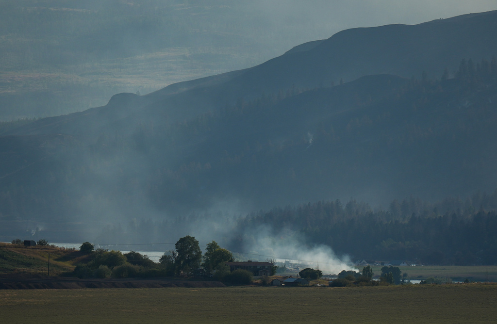 The Bradley Creek wildfire burns near a home, in Vernon, British Columbia, Monday, Aug. 3, 2026. (Darryl Dyck/The Canadian Press via AP)