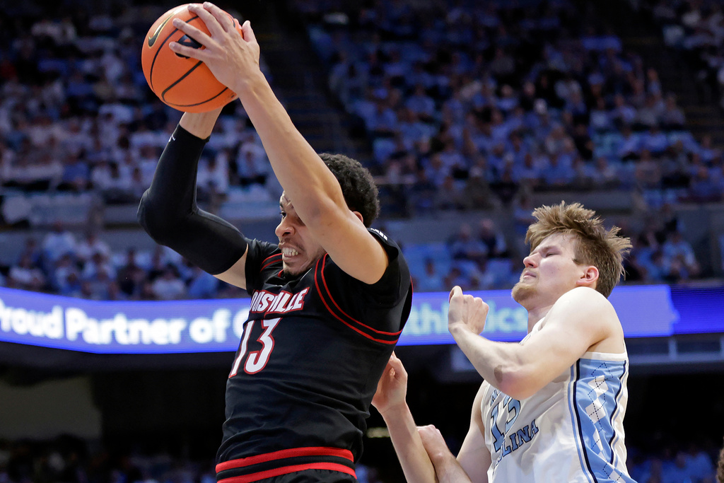 Louisville forward Sananda Fru, left, pulls down a rebound over North Carolina center Henri Veesaar, right, during the first half of an NCAA college basketball game Monday, Feb. 23, 2026, in Chapel Hill, N.C. (AP Photo/Chris Seward)