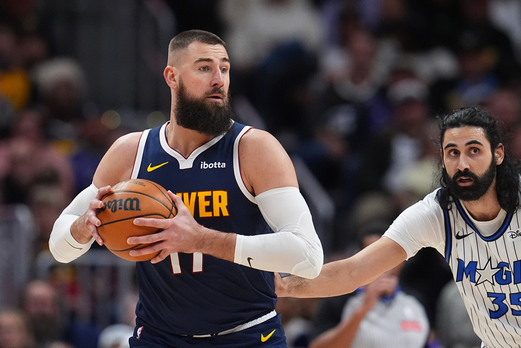 Denver Nuggets center Jonas Valančiūnas, left, looks to pass the ball as Orlando Magic center Goga Bitadze defends in the first half of an NBA basketball game, Thursday, Dec. 18, 2025, in Denver. (AP Photo/David Zalubowski)