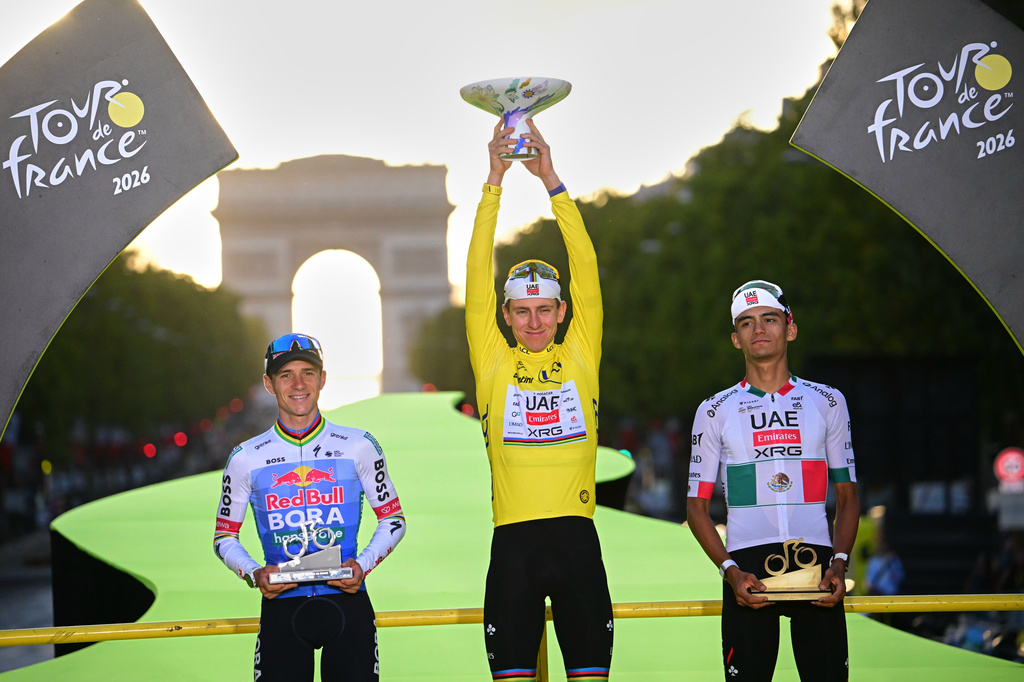 Slovenia's Tadej Pogacar, wearing the overall leader's yellow jersey, celebrates on the podium after winning the Tour de France cycling race alongside Belgium's Remco Evenepoel, second, and Mexico's Isaac Del Toro, third, in Paris, Sunday, July 26, 2026. (AP Photo/Bernard Papon/Pool Photo via AP)