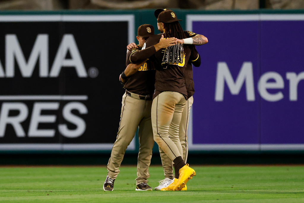 San Diego Padres left fielder Ramon Laureano (5), from left, San Diego Padres right fielder Fernando Tatis Jr. (23) and San Diego Padres center fielder Jackson Merrill (3) embrace upon defeating the Los Angeles Angels at the end of the ninth inning of a baseball game, Saturday, April 18, 2026, in Anaheim, Calif. (AP Photo/Caroline Brehman)