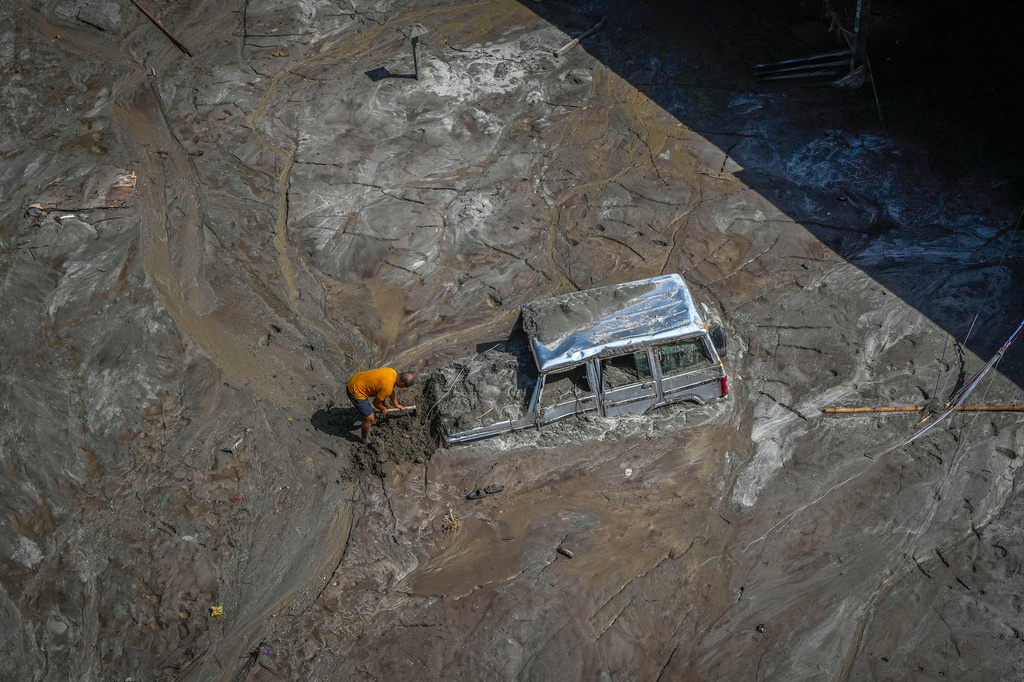 FILE -A man tries to recover a vehicle submerged in mud in a flood-affected area along the Teesta river in northeastern India, Oct. 8. 2023. (AP Photo/Anupam Nath, File)