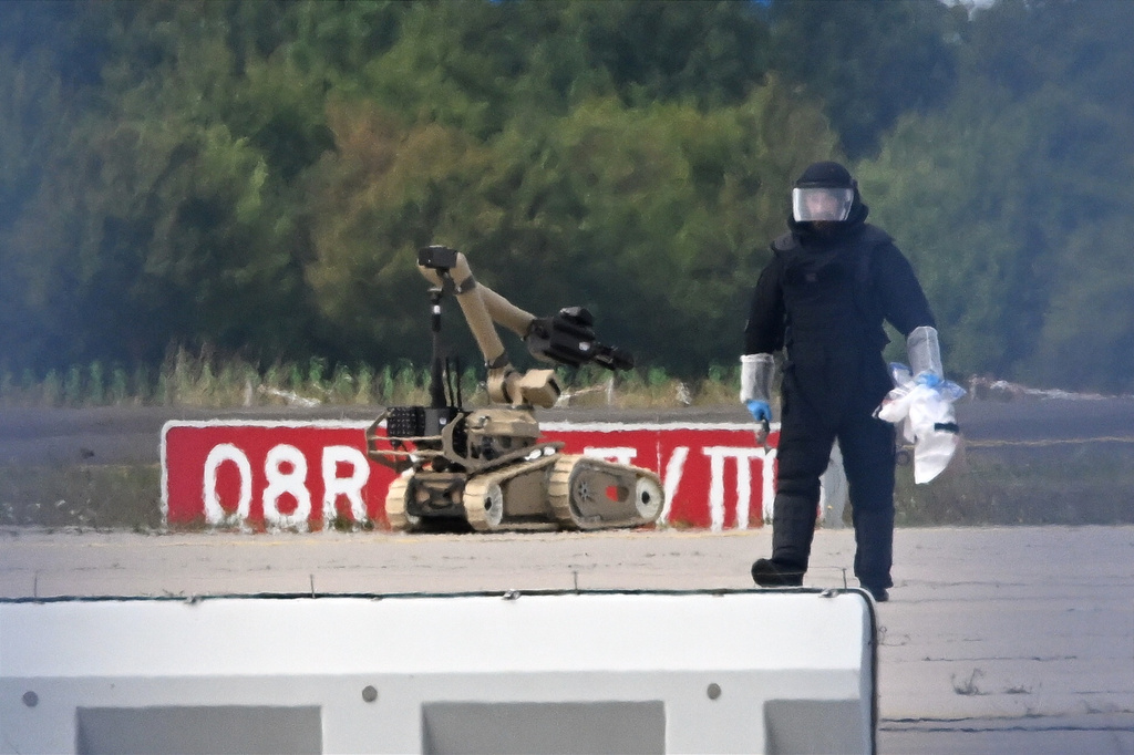 A forensic technician works alongside a bomb-disposal robot near a Ukrainian aircraft at Leipzig/Halle Airport, where a drone with an explosive device was found and a detonator was removed from the object, in Schkeuditz, Germany, Wednesday Aug. 5, 2026. (Hendrik Schmidt/dpa via AP)