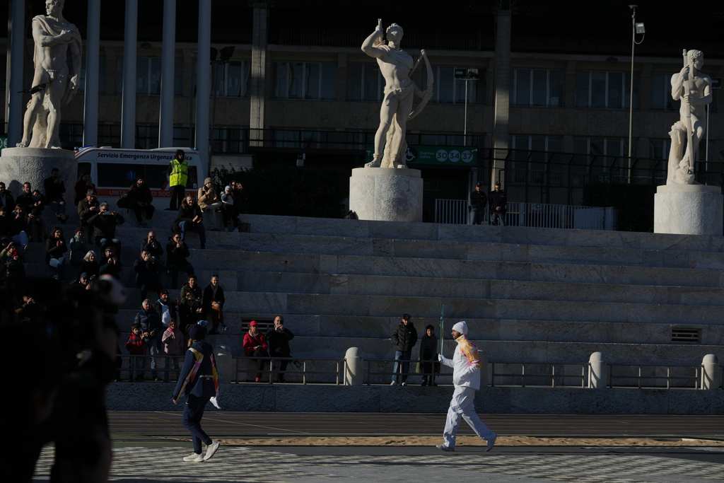 Italian swimmer Gregorio Paltrinieri carries the 2026 Milan Cortina Winter Olympics torch in Rome as it begins its journey through Italy, Saturday, Dec. 6, 2025, a journey that will conclude in Milan in February 2026. (AP Photo/Andrew Medichini)