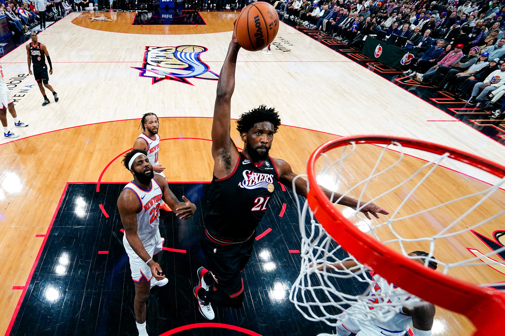 Philadelphia 76ers' Joel Embiid, center, goes up for the shot as New York Knicks' Mitchell Robinson, left, and Miles McBride, right, looks on during the first half of an NBA basketball game, Saturday, Jan. 24, 2026, in Philadelphia. (AP Photo/Chris Szagola)