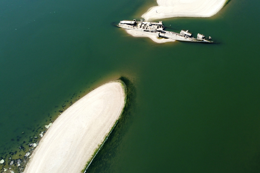 The wreckage of a WWII German warship emerges, due to the drought, in front of Djerdap II, a large dam on the Danube River, between Romania and Serbia, near Prahovo, Serbia, Tuesday, Aug. 4, 2026. (AP Photo/Darko Vojinovic)