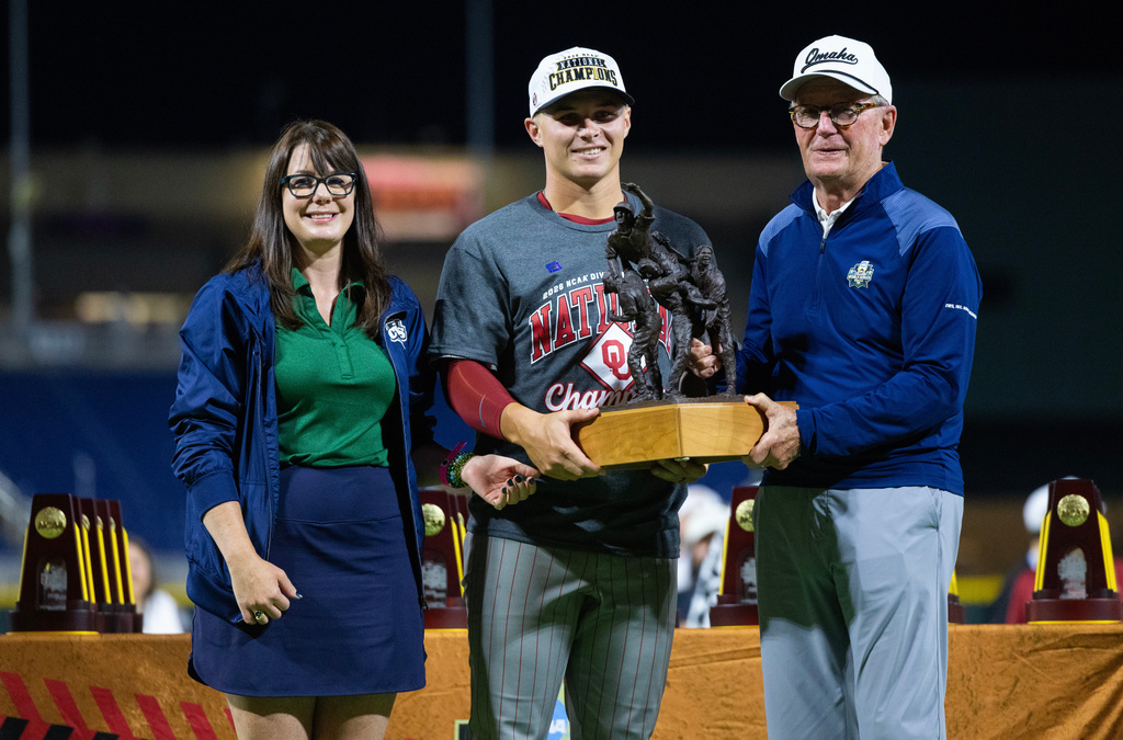 Jack Diesing Jr., right, chairman and president of the Board College World Series of Omaha, Inc., and his daughter, vice president Lisa Diesing, left, present the John D. Diesing Sr. award to Oklahoma's Jaxon Willits following Oklahoma's win against North Carolina in Game 3 of the NCAA College World Series baseball finals in Omaha, Neb., Monday, June 22, 2026. (AP Photo/Rebecca S. Gratz)