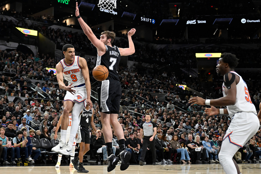 New York Knicks guard Kevin McCullar Jr. (9) passes to Knicks center Ariel Hukporti as he is guarded by San Antonio Spurs center Luke Kornet (7) during the first half of an NBA basketball game, Wednesday, Dec. 31, 2025, in San Antonio. (AP Photo/Darren Abate)