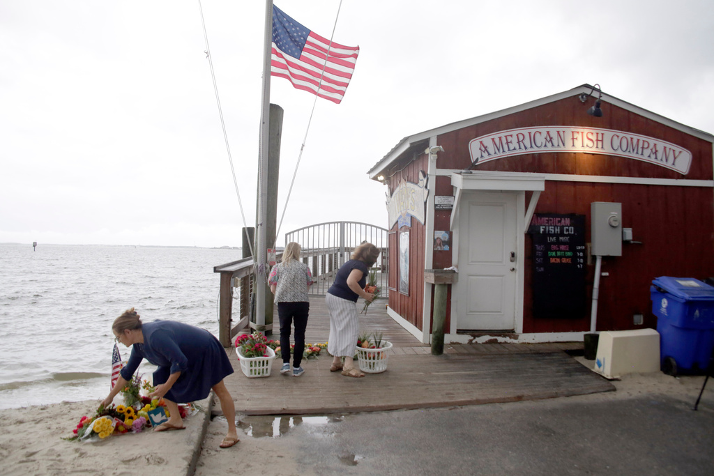 People place flowers in front of the American Fish Company following a fatal shooting that occurred the night before, Sunday, Sept. 28, 2025, in Southport, N.C. (AP Photo/Chris Seward)