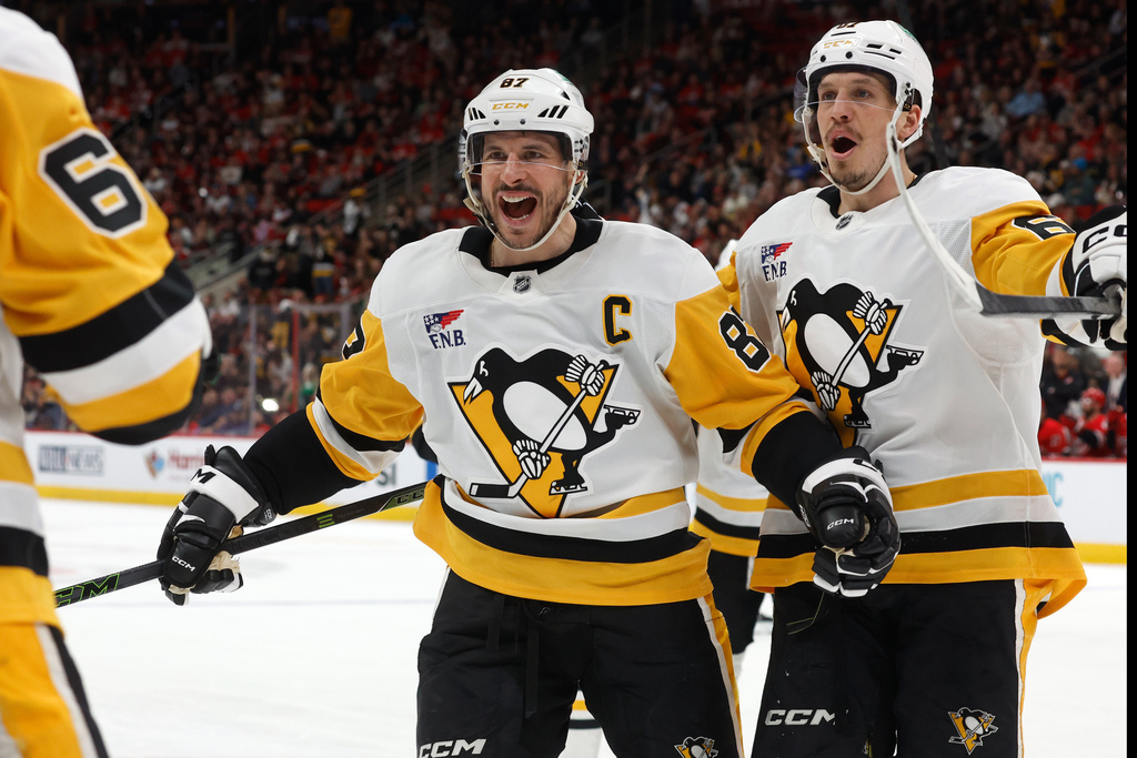 Pittsburgh Penguins' Sidney Crosby (87) comes to congratulate teammate Erik Karlsson, left, on his goal with Rickard Rakell, right, during the third period of an NHL hockey game against the Carolina Hurricanes in Raleigh, N.C., Wednesday, March 18, 2026. (AP Photo/Karl DeBlaker)