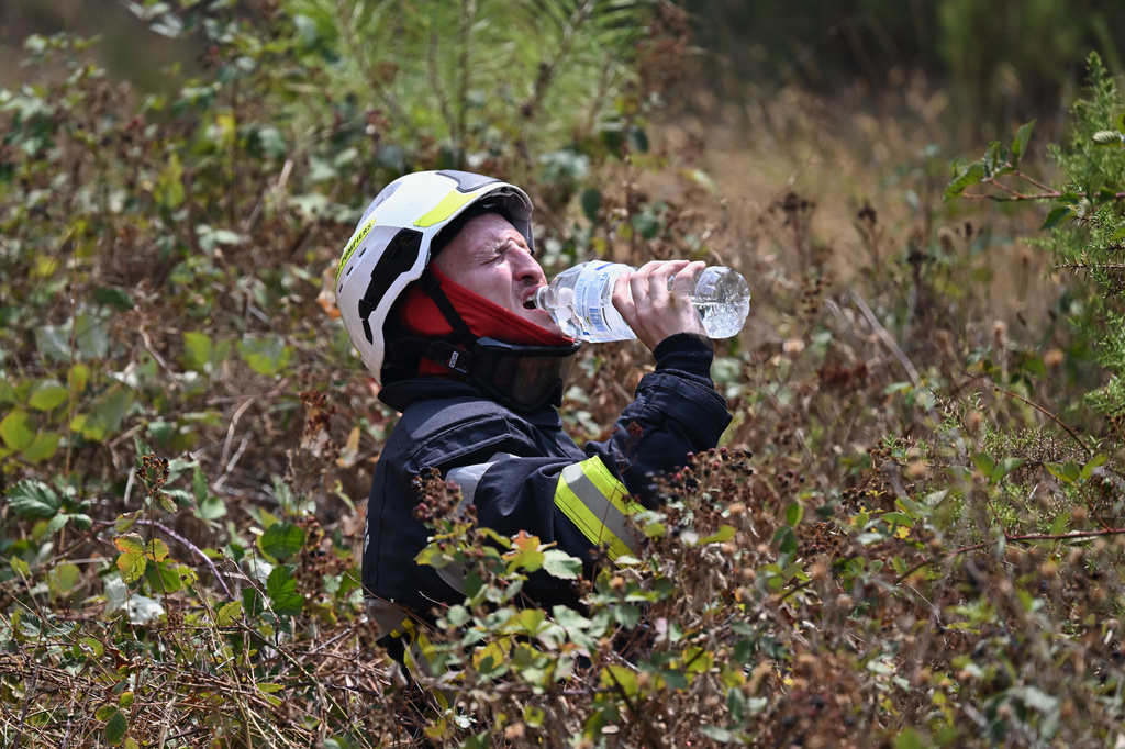 A firefighter takes a drink of water while battling a wildfire near Le Temple, outside, Bordeaux, France, Sunday, July 26, 2026. (AP Photo/Emma Da Silva)